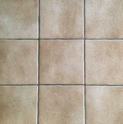 Beige Fliesen mit grauen Fugen.